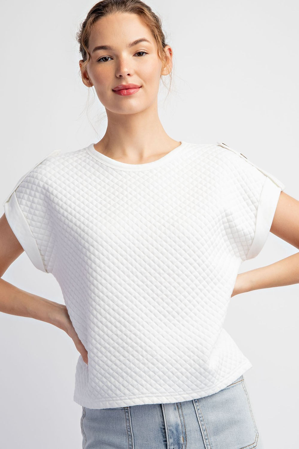 Woman wearing a textured white t-shirt against a plain background