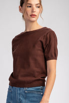 Woman wearing a brown sweater and blue jeans on a white background