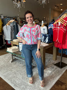 Woman in a floral top and jeans standing in a clothing store.