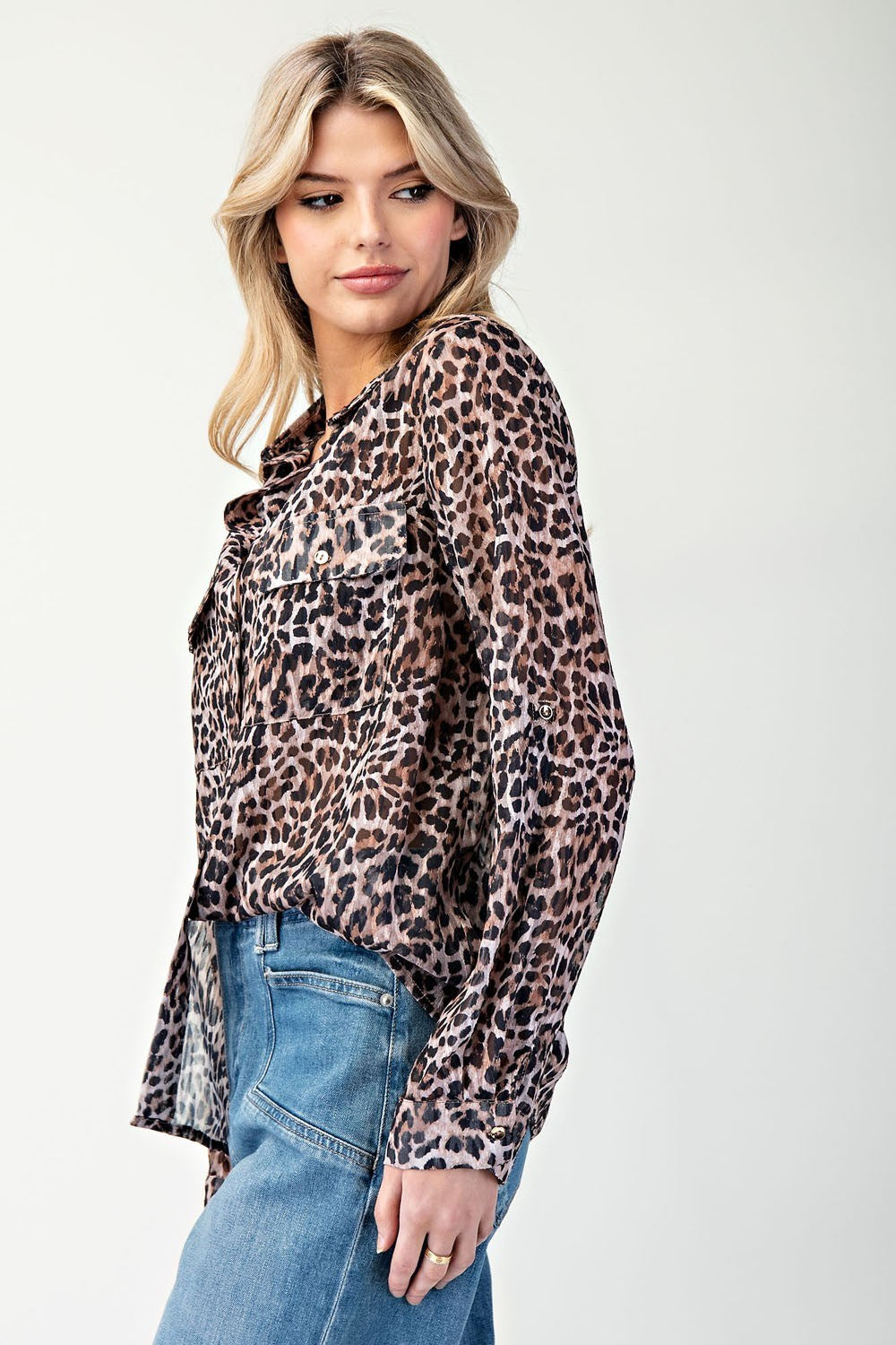 Woman wearing a leopard print shirt and blue jeans on a white background