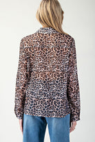Person wearing a leopard print blouse with blue jeans on a white background