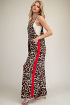 Woman wearing a leopard print dress with a red stripe on a plain background