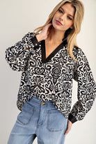 Woman wearing a black and white patterned blouse with blue jeans on a plain background