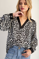 Woman wearing a black and white patterned blouse with a plain background
