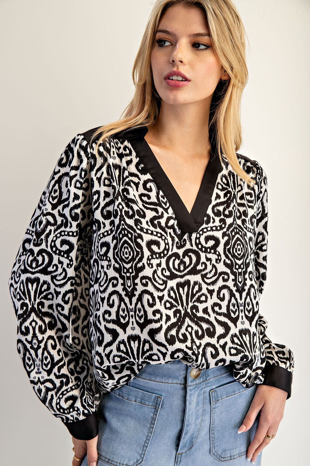 Woman wearing a black and white patterned blouse with a plain background