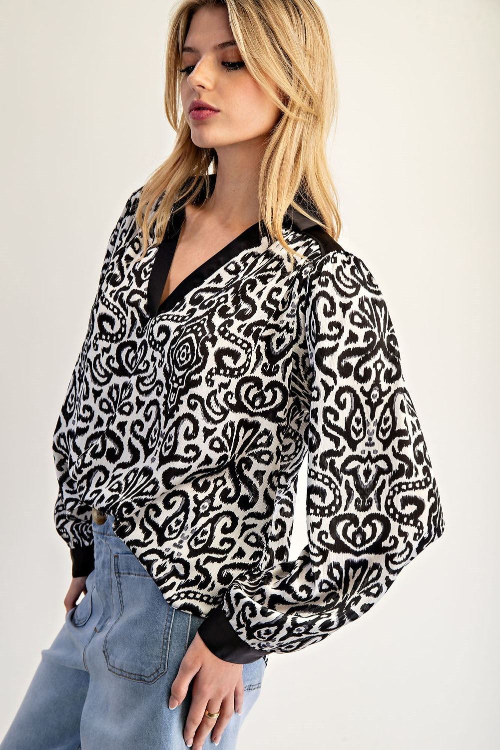 Woman wearing a black and white patterned blouse with a plain background