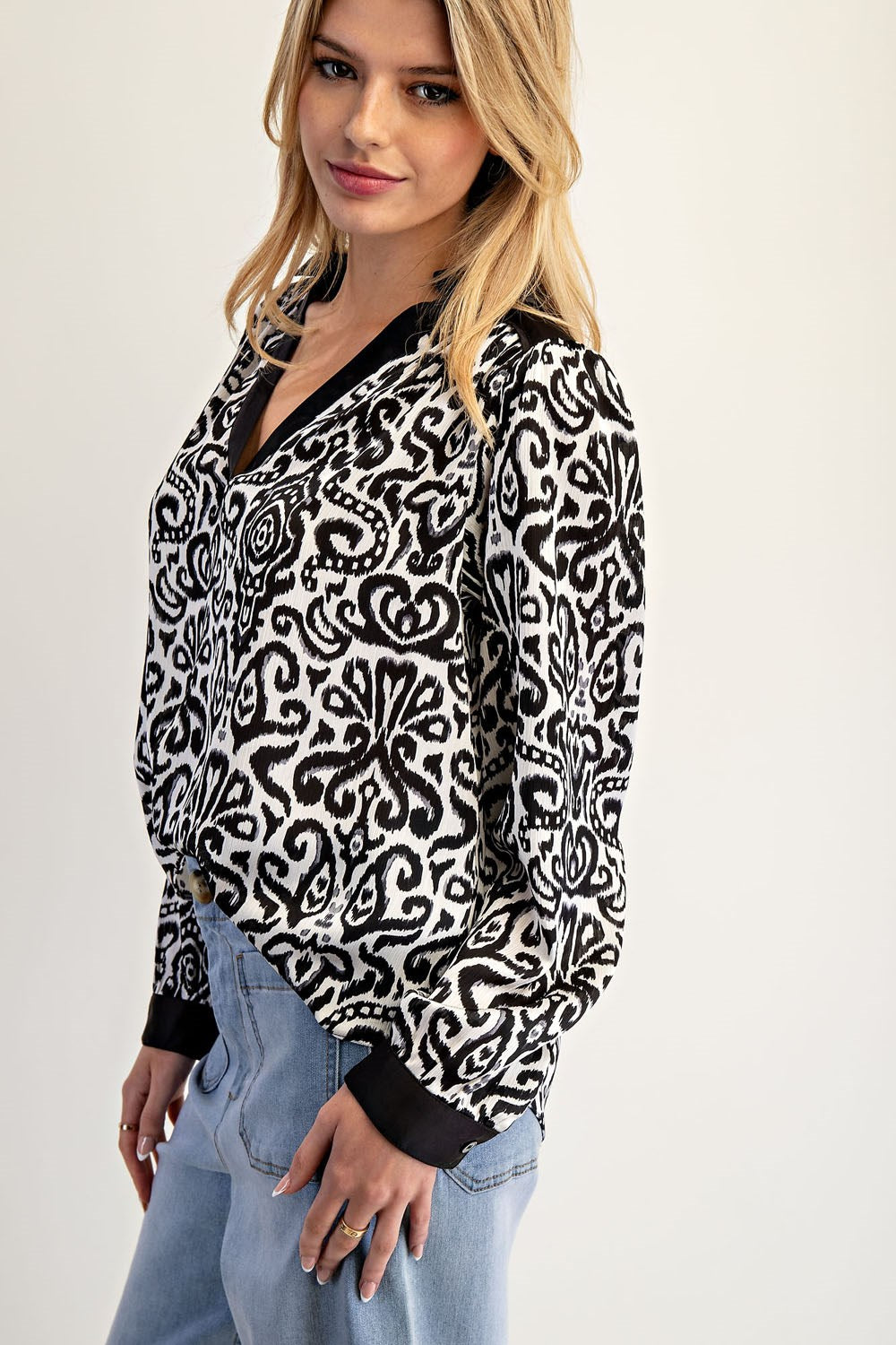 Woman wearing a black and white patterned blouse with a plain background