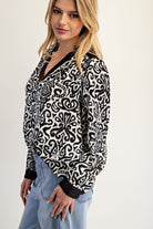 Woman wearing a black and white patterned blouse with a plain background