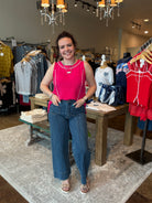 Woman in a pink top and blue jeans standing in a clothing store.