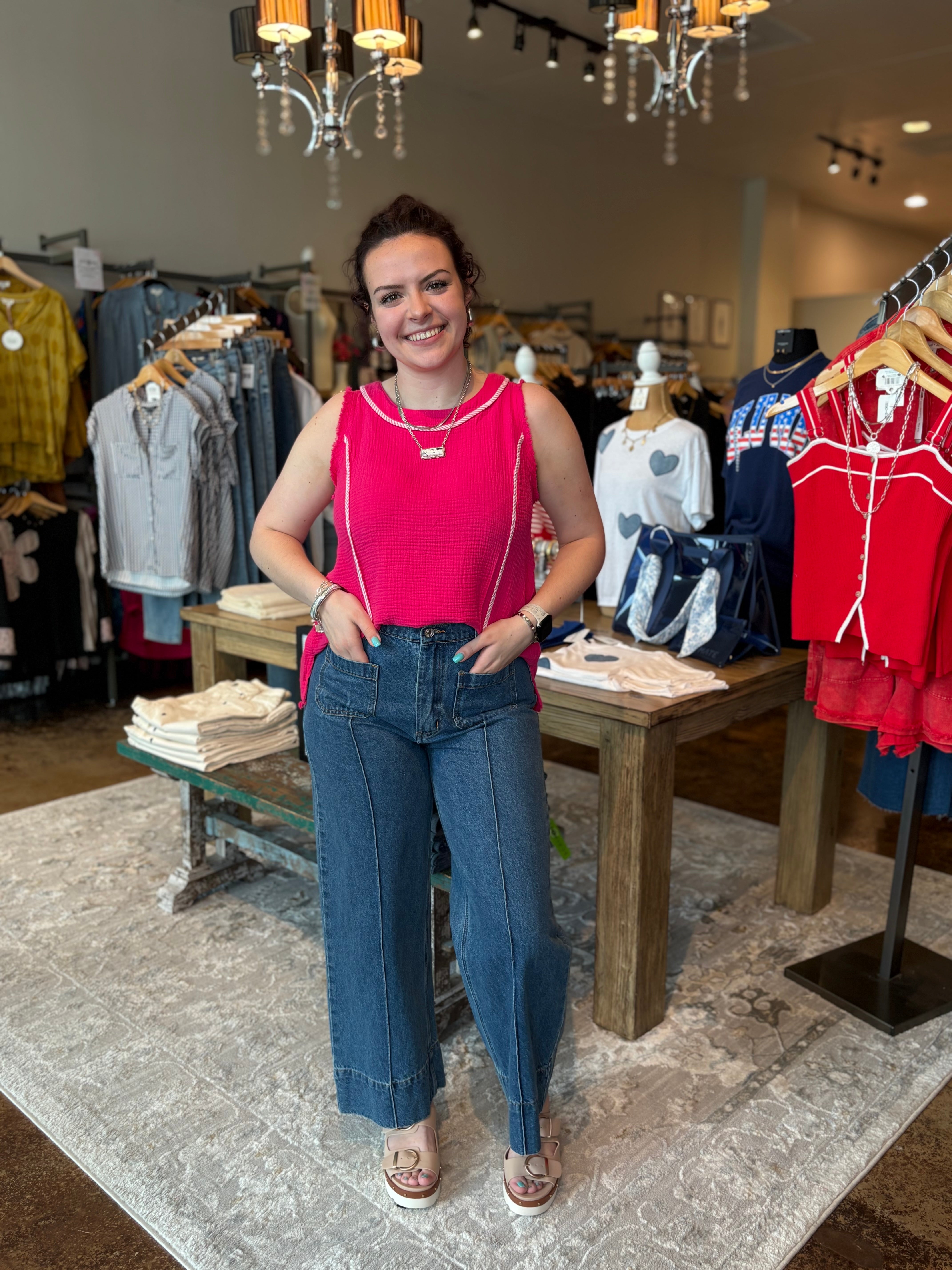 Woman in a pink top and blue jeans standing in a clothing store.