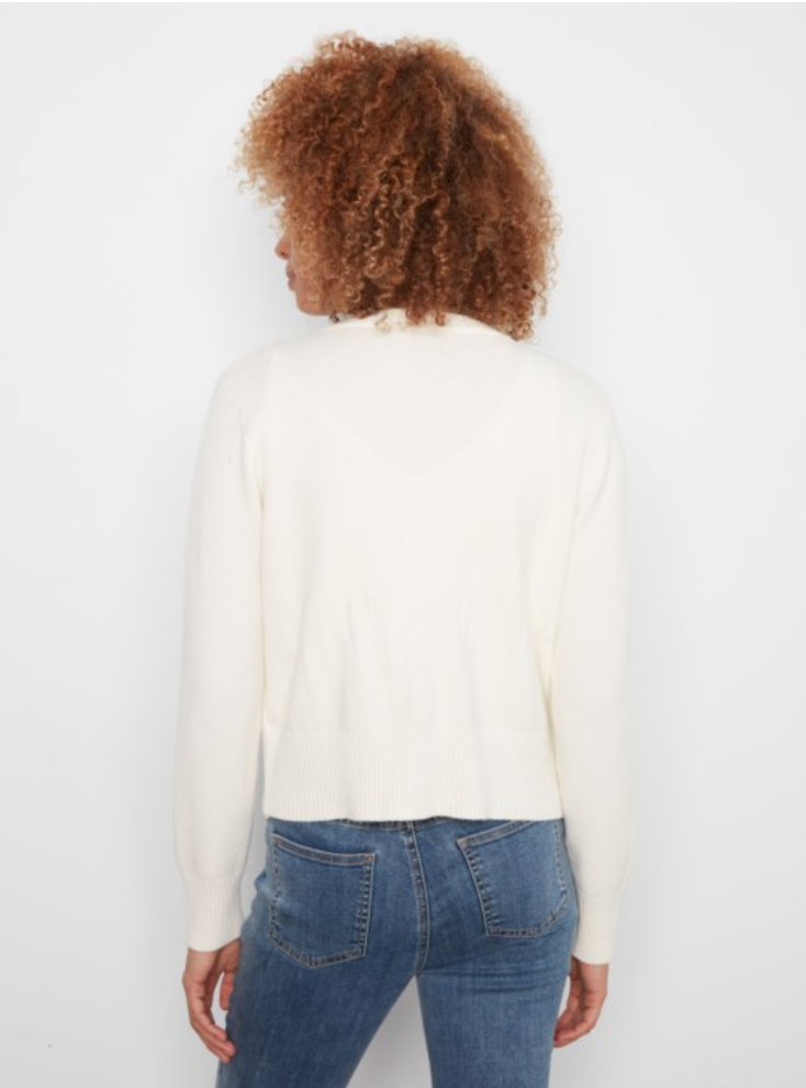 A woman with curly brown hair is shown from behind wearing a cream-colored knit sweater and blue jeans against a plain white background.