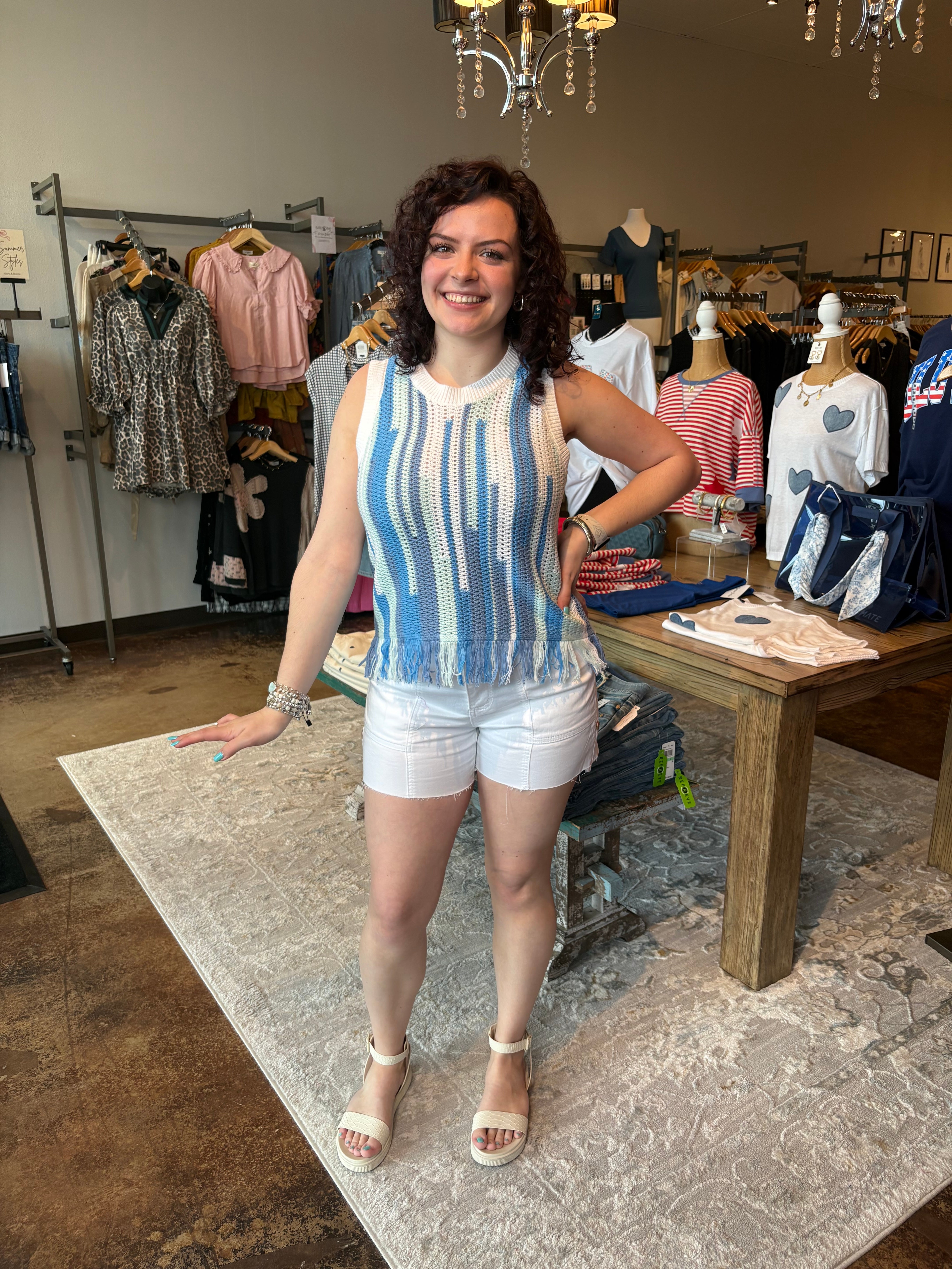 Woman wearing a crocheted sleeveless top. Blue and light green stripes on the tank