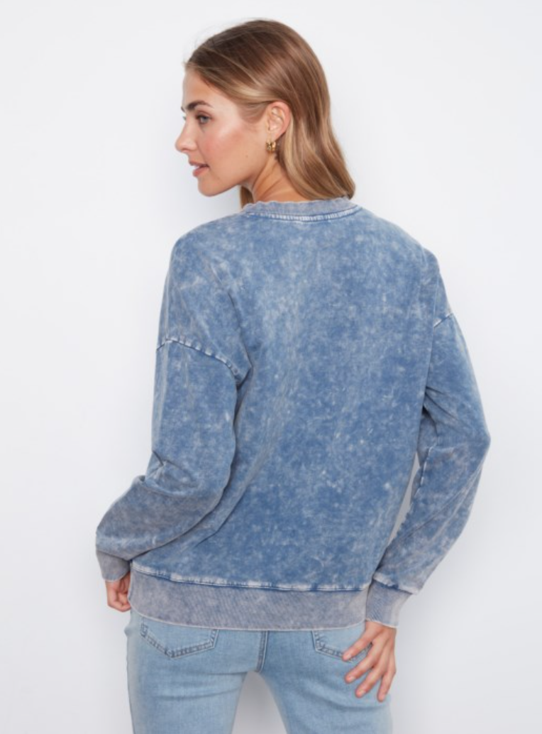 A woman shown from the back wearing a blue acid-wash crewneck sweatshirt and light-wash jeans against a plain white background.