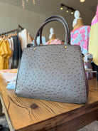 Gray textured handbag on a wooden table in a clothing store