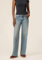 Person wearing light blue jeans and a black top on a beige background