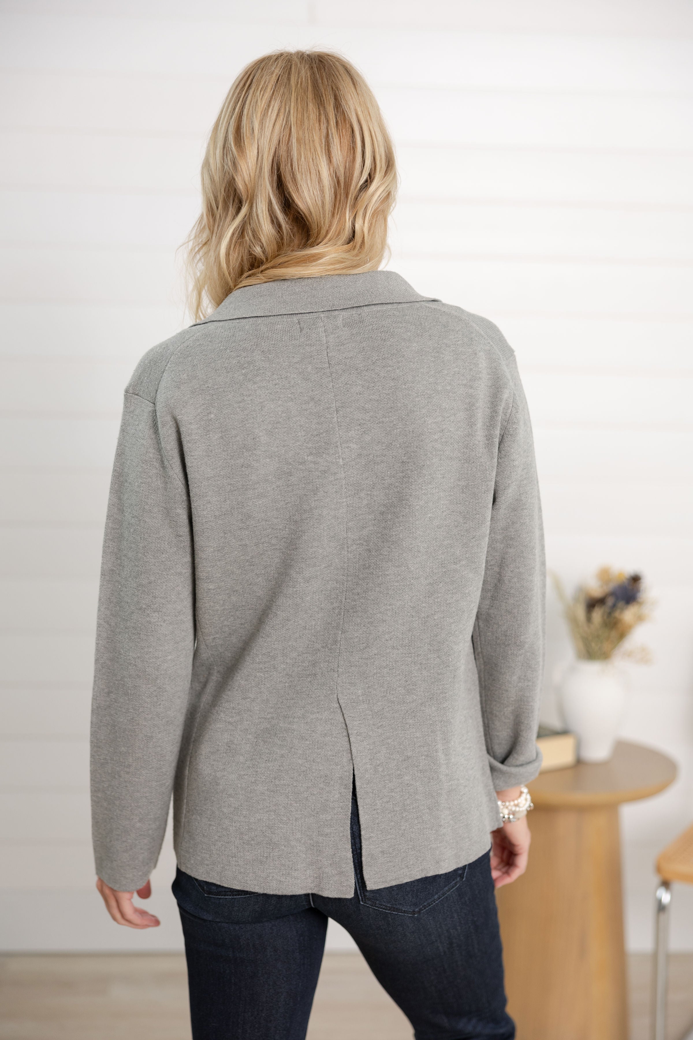 Person wearing a gray cardigan in an indoor setting