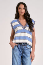 Woman wearing a blue and white striped sleeveless top with jeans on a plain background
