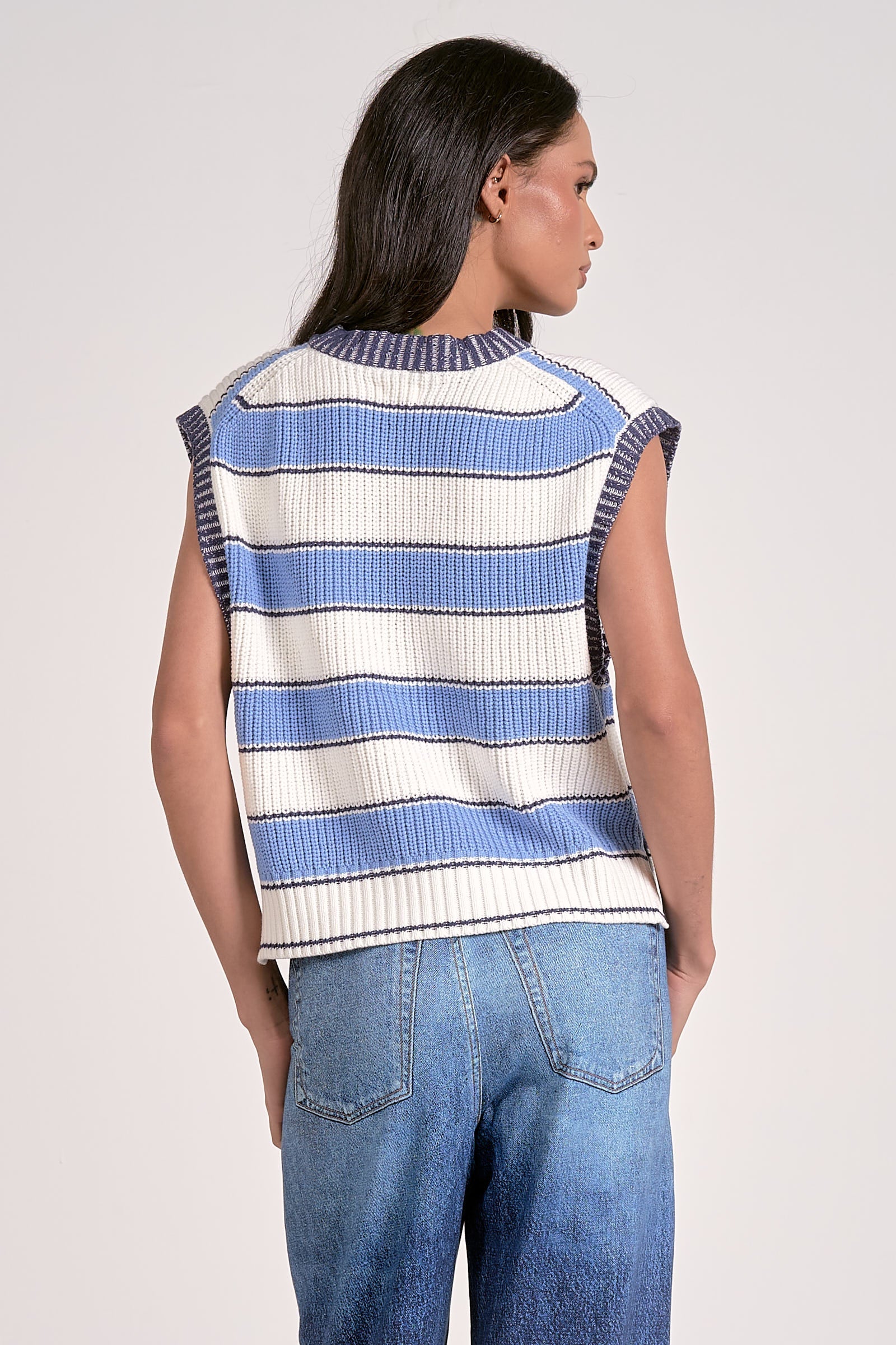 Woman wearing a blue and white striped sleeveless top with jeans.