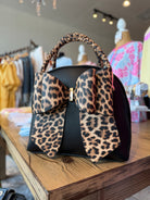 Leopard print handbag on a wooden surface with a store interior in the background