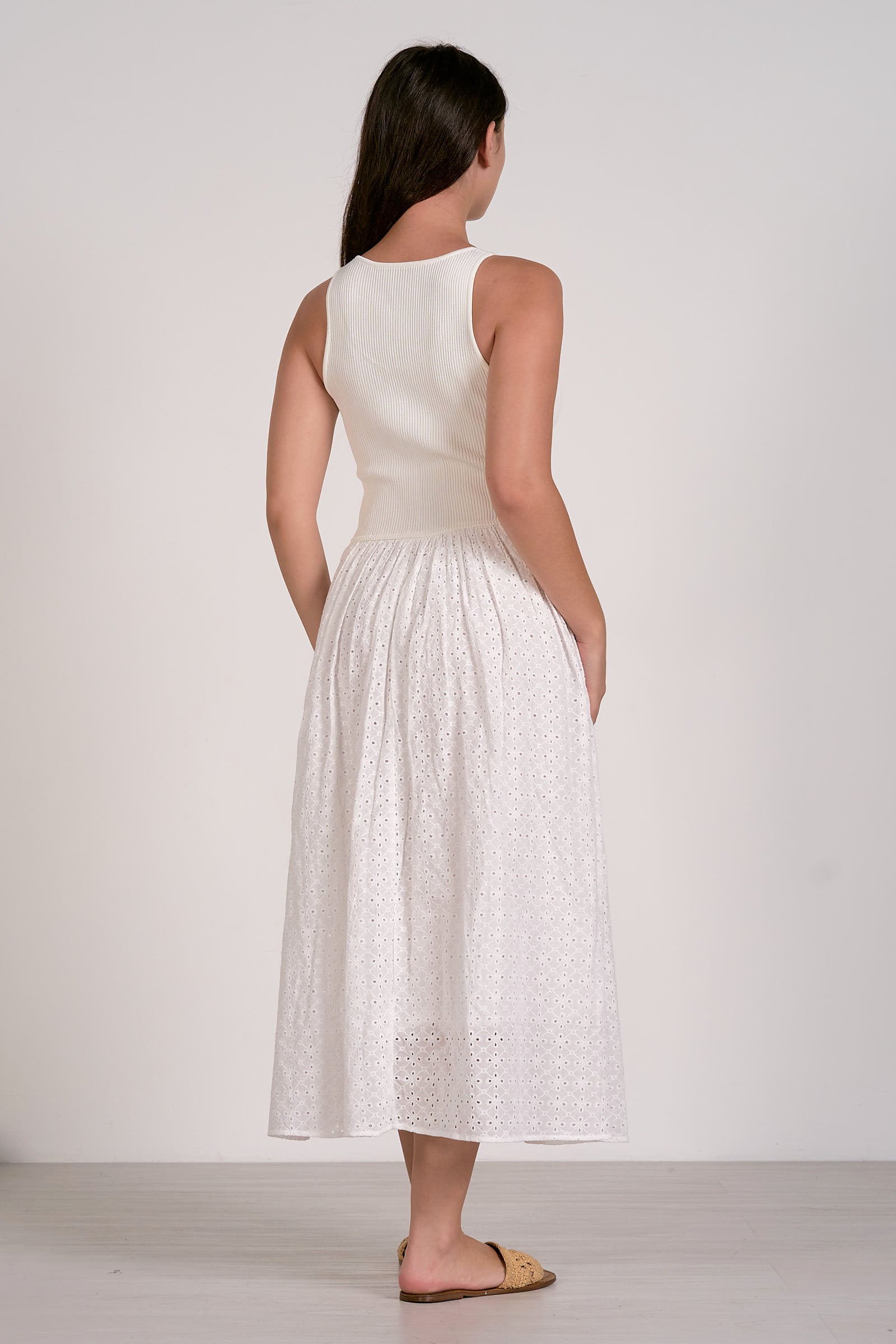 Woman wearing a white sleeveless dress with a plain background