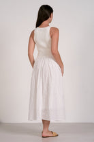Woman wearing a white sleeveless dress with a plain background