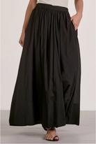 Person wearing a black skirt on a plain background