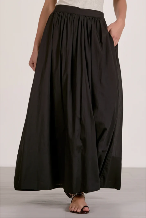 Person wearing a black skirt on a plain background