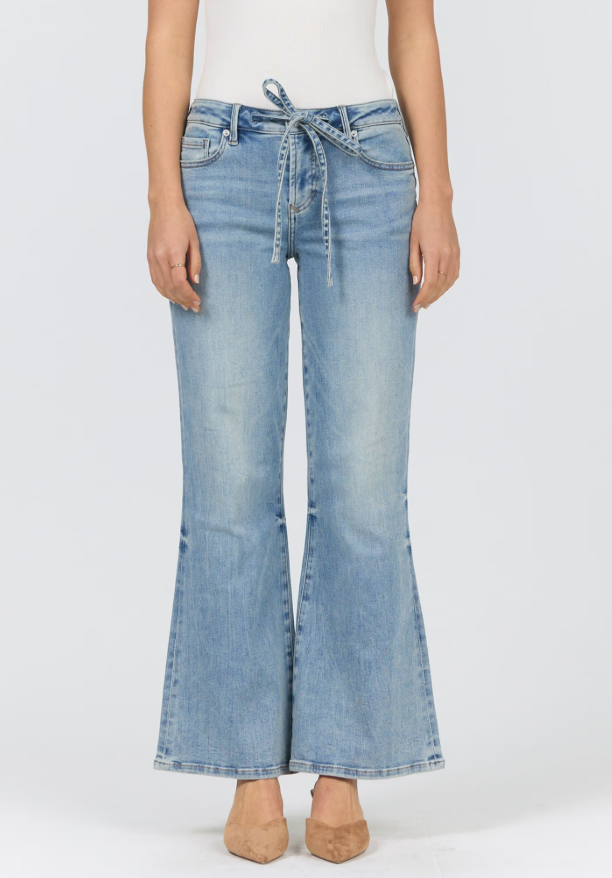 A model wearing light-wash blue flare jeans with a drawstring waist, paired with a white top and beige heels, shown against a plain white studio background.