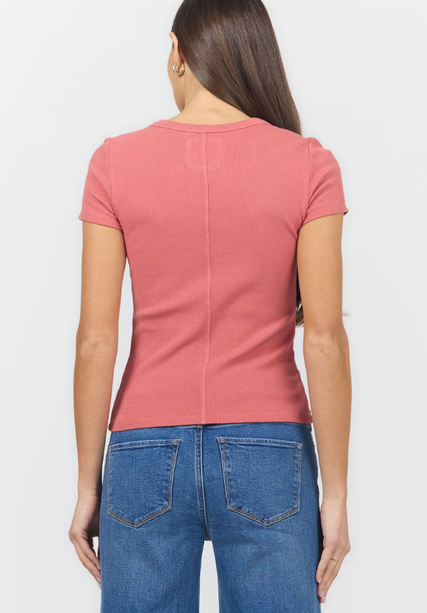 A woman shown from the back wearing a fitted short-sleeve ribbed pink top and blue jeans against a plain light background.