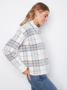 Woman wearing a plaid jacket and jeans on a white background