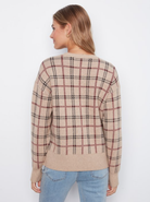 A woman shown from the back wearing a beige knit sweater with a brown and black plaid pattern, paired with light blue jeans, against a plain white background.