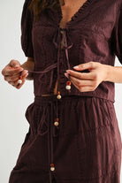 Close-up of brown embroidered top tie-front closure with decorative beaded ends