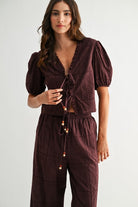 Model wearing brown embroidered puff sleeve tie-front top, full front view
