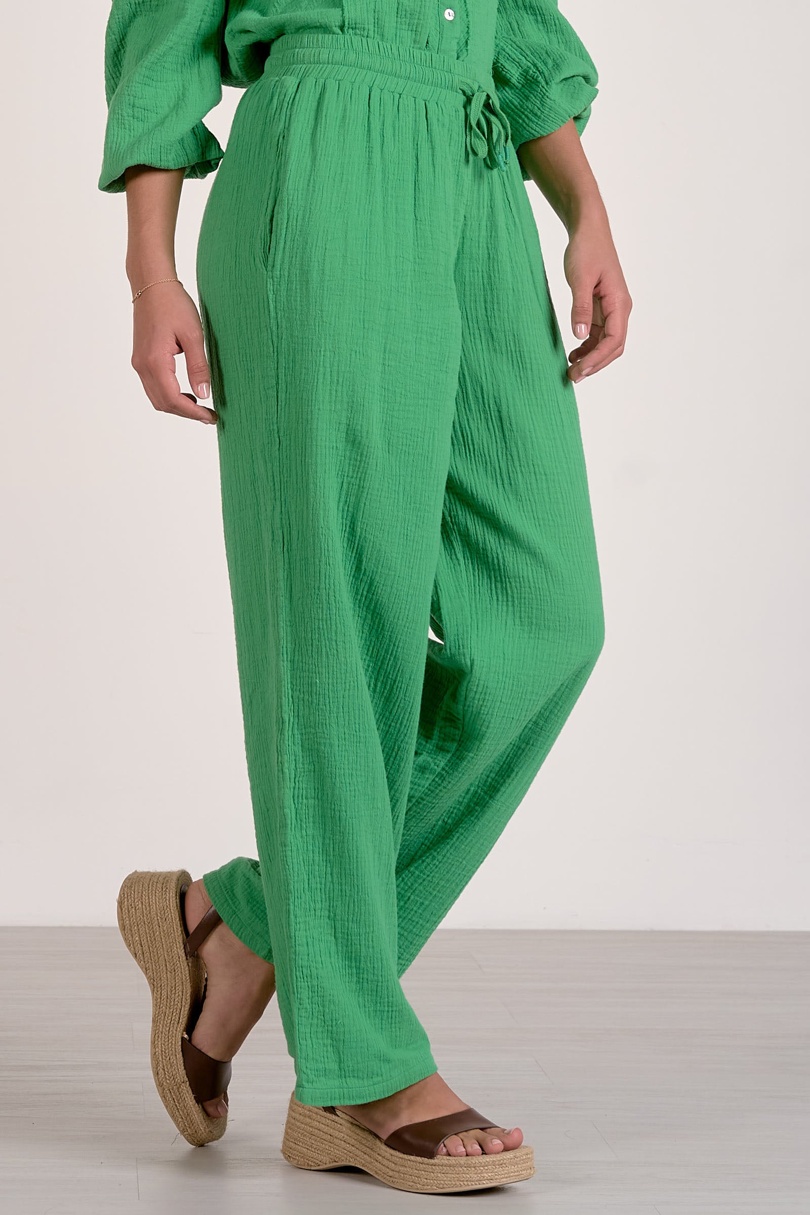Person wearing a green outfit with wide-leg pants on a white background
