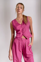 Woman wearing a pink sleeveless top and pants against a plain background