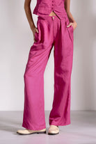 Person wearing bright pink pants and a matching top on a plain background