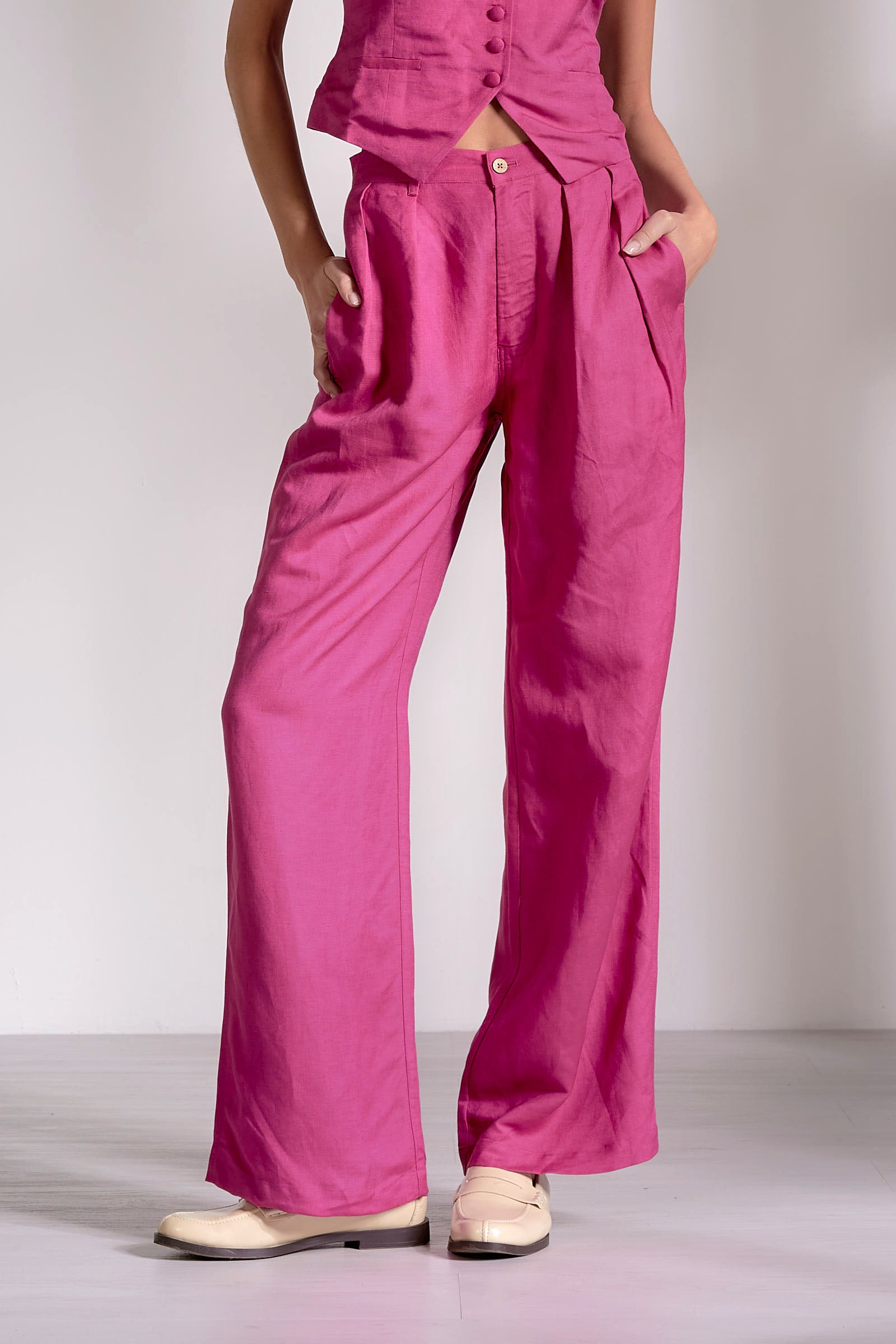 Person wearing bright pink pants and a matching top on a plain background